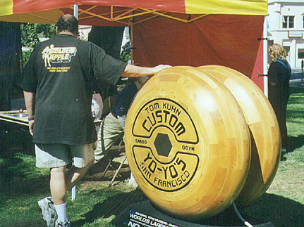 Here is a photo of a man standing along side the worlds largest yo yo made by Tom Kuhn of San Francisco. 